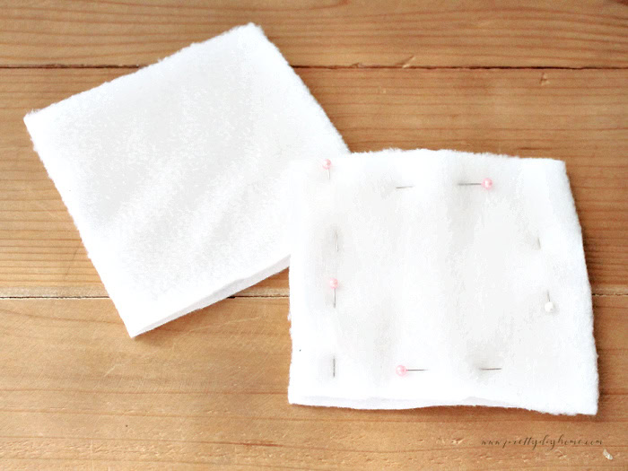 Four squares of white fleece in 2 stacks, one of the stack is pinned.