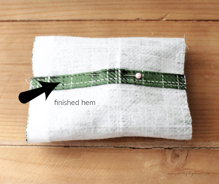 A diy hand warmer having its cover made, there is an arrow pointing to the finished hem for the envelope cover.