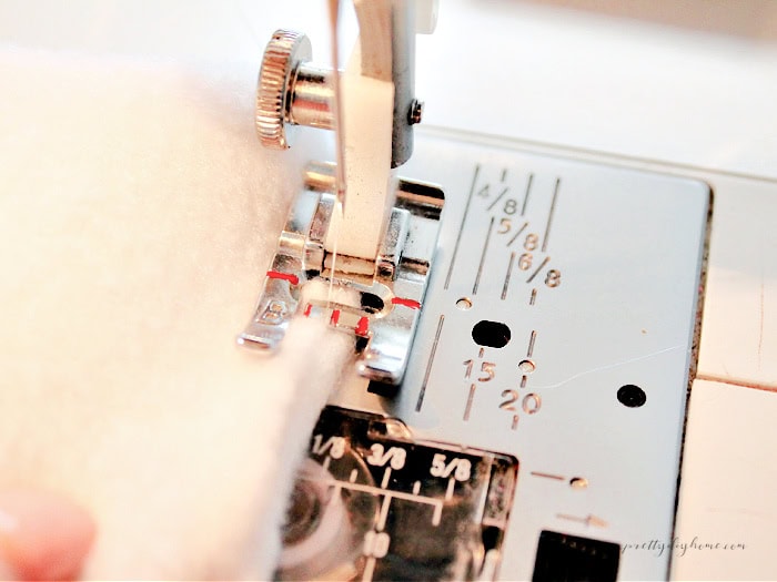 Close up of the sewing machine needle outlining the placement for the zig zag stitch to sew a hand warmer closed.