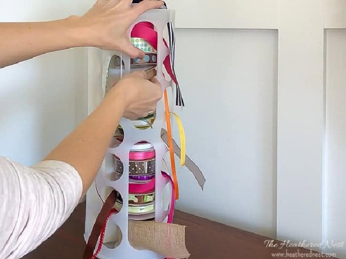 An Ikea organizer filled with ribbons and each ribbon has a hole to pull the end through.