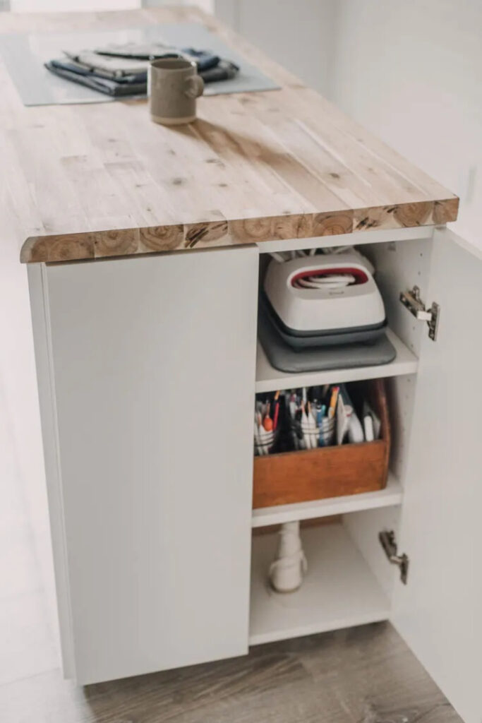 A rolling DIY craft table with a wooden top, and rollers on the bottom.  This craft table has cupboard doors for storage.