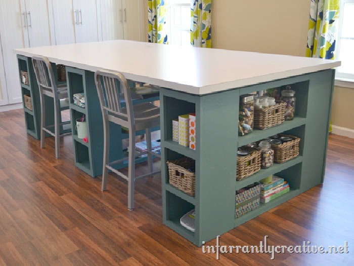 A large craft tables held up with 3 sections of shelving with storage.