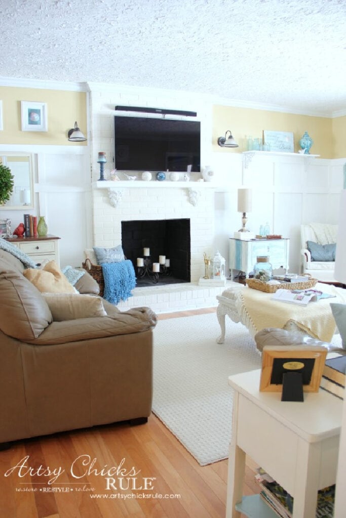 A family room decorated with an old fireplace refinished with white paint, and a mantel.  