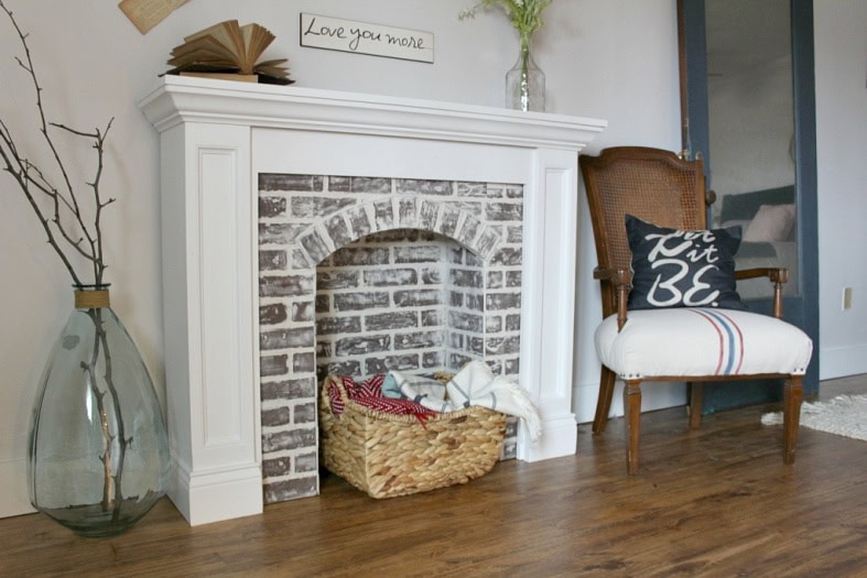 A faux fireplace featuring lots of brick, a elaborate white fascade and pretty white mantel. 