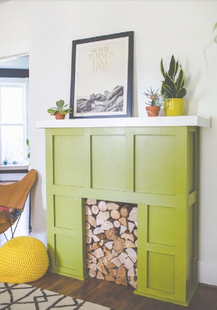 A DIY green faux fireplace surround with log slices for the firebox.