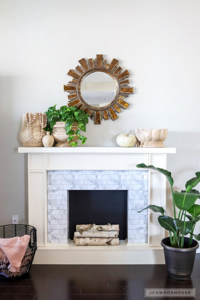 A beautiful white faux fireplace with a mantel, and base.  The firebox is black and the front is made with faux tiles.