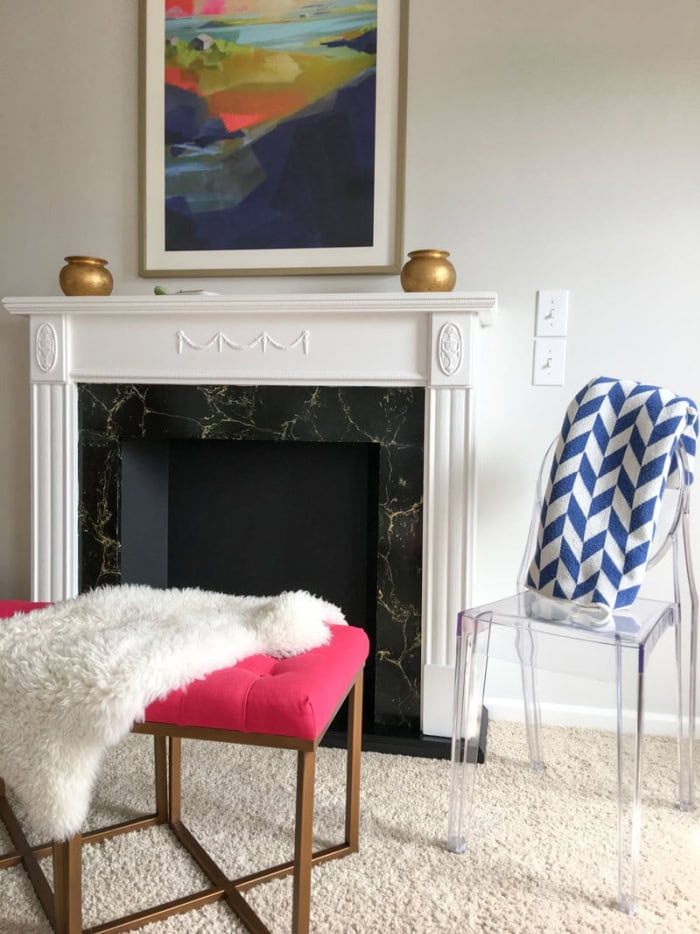 A DIY white faux fireplace surround with black and marble firebox.  Its surrounded with bright and cheerful modern furniture.