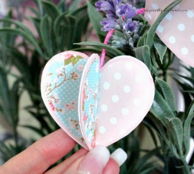 Close up of a 3D paper Valentine heart sewn onto twine with lavender greenery in the background