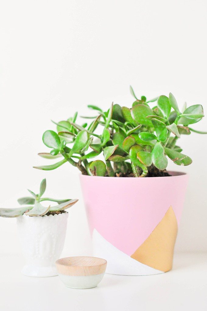 A geometric painted terracotta flower pot in pinks and metallic gold. A very pretty clay pot painting design.