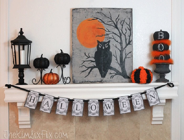 A Halloween mantel featuring a large DIY wood Halloween sign with an owl, orange moon and branches.