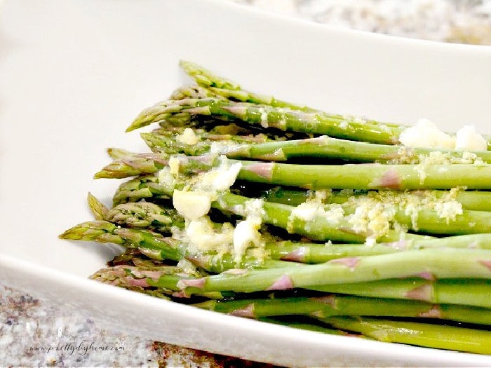 A bowl filled with fresh asparagus, garlic melted butter and parmesan being mixed together for a Christmas appetizer.