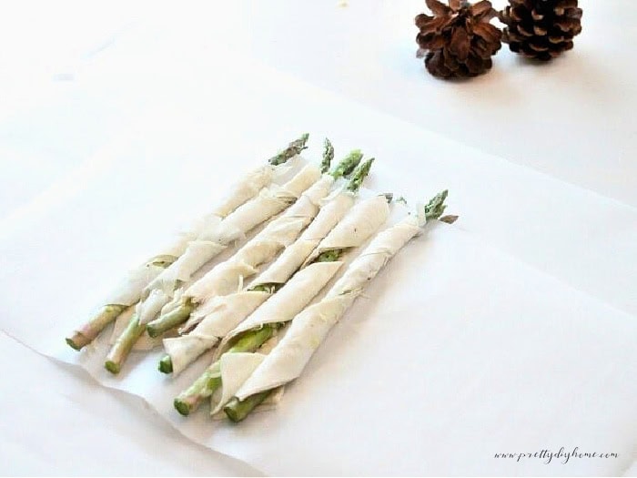 Asparagus Chrismas appetizers being bundled together in parchment paper for freezing.  An easy makeahead appetizer recipe for Christmas.