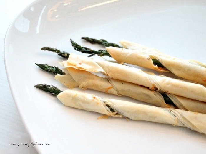 Several pieces of phyllo wrapped asparagus appetizers.  Each asparagus is wrap in a curl of pretty golden brown baked filo pastry.  