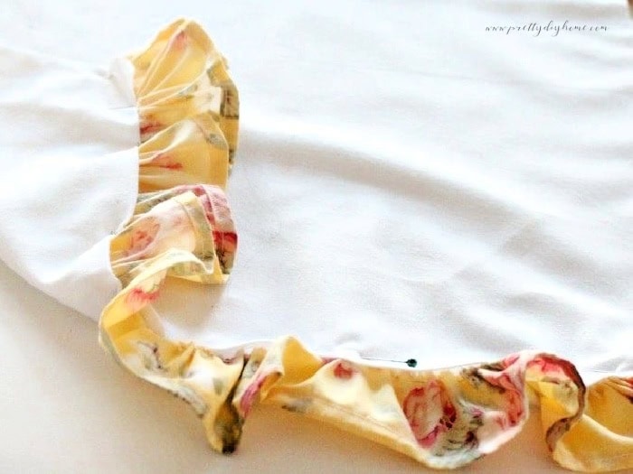 Attaching a gathered ruffle to the bottom of a handmade children’s apron, pinned in place and ready to sew
