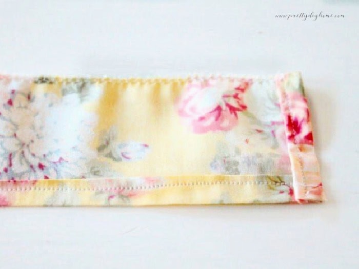 Sewing a ruffle for a handmade children’s apron showing the folded bottom hem and zigzag stitched top edge before gathering