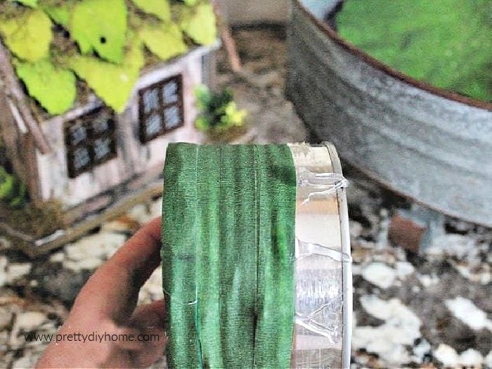 A tin can for a DIY fairy garden idea, being wrapped in green tape for safety.