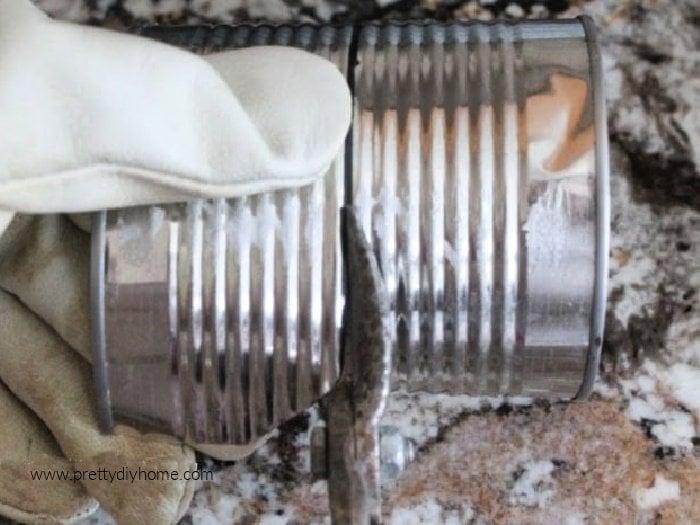 Cutting a tin can to height safely using tin snips and wearing a heavy leather glove.