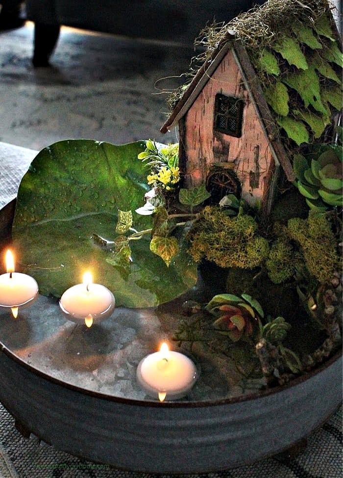 A miniature DIY fairy garden for indoors with  a pool, succulents, and fairy house. 