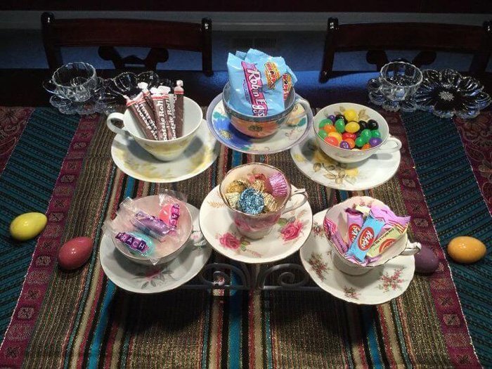 A serving set made with six different teacups, each at a different level with different treats inside.