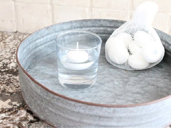 A floating candle in a glass of water.  Testing the height of a container to make a DIY fairy garden indoors.