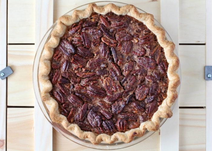 Looking at a entire chocolate pecan pie with bourbon from the top. The pie is dark luscious brown and you can see the light crust encircling the outside.