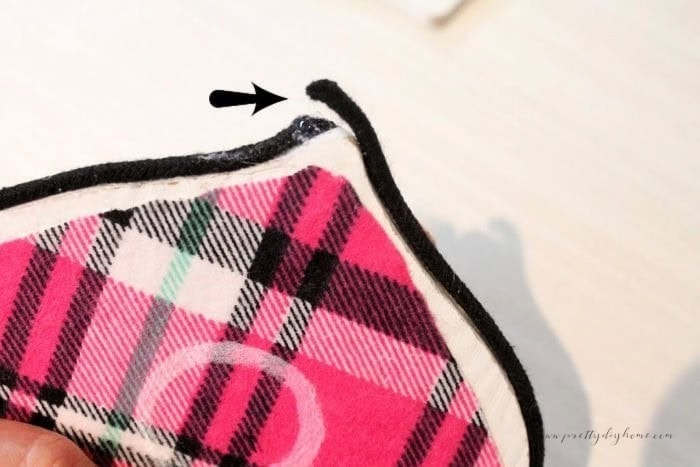 Layering the black cord ends neatly so they meet exactly at the back of the flannel Christmas ornament.