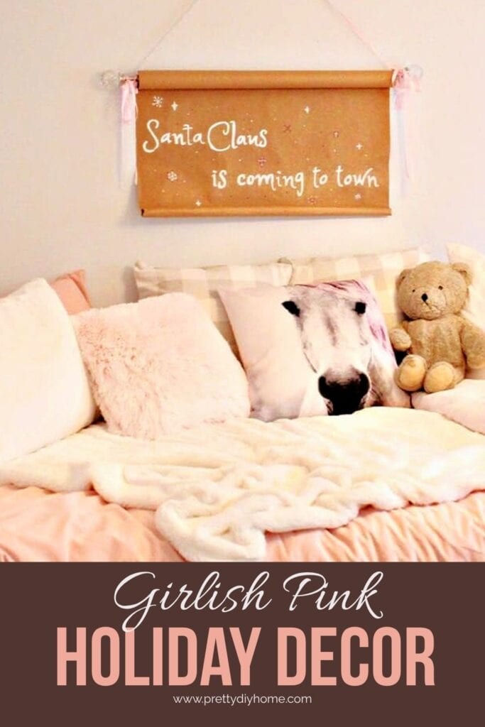 A pretty little girls Christmas bedroom decorated with a homemade paper scroll sign that says "Santa Claus is coming to town" The sign is decorated with pink ribbon to match the bed linens and pillows.