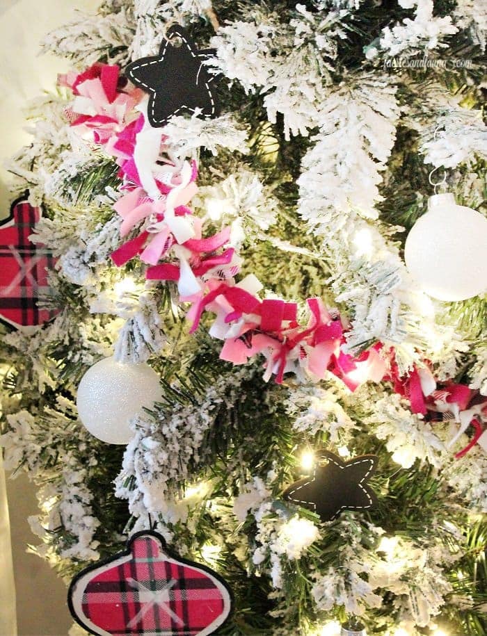 Close up of a pink DIY Christmas garland on a tree decorated with white sparkly ornaments, white light and matching plaid fabric onion-shaped ornaments.