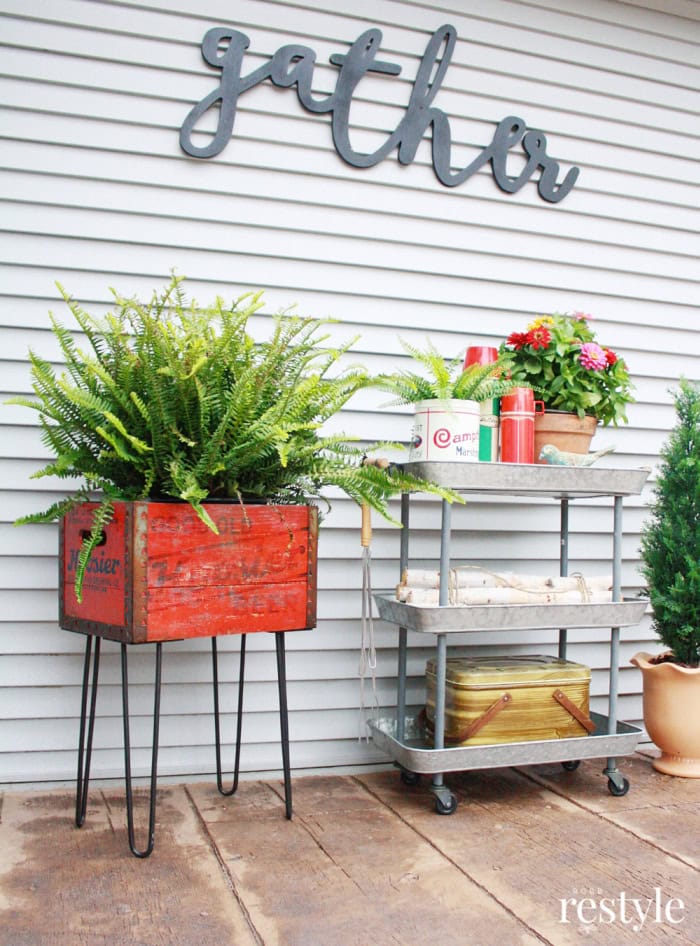 Repurposed vintage wooden crate planter with greenery on hairpin legs for spring decor.