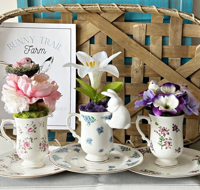 Vintage teacups used as small planters with flowers for spring decor.