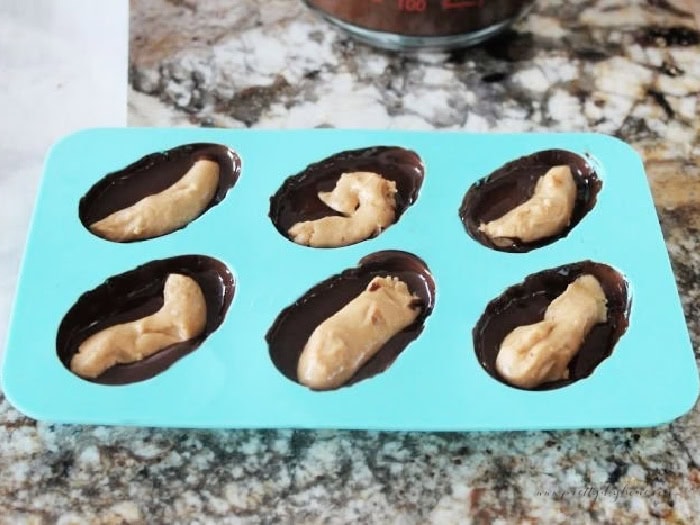 A silicone Easter egg chocolate mold filled with a coating of chocolate on the outside and a peanut butter filling.  