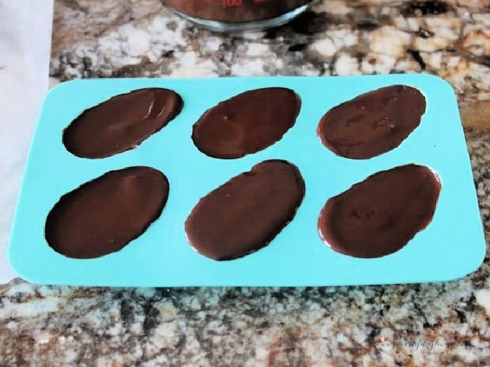 A chocolate silicone mold filled with six chocolate peanut butter Easter egg.  They still need to harden.