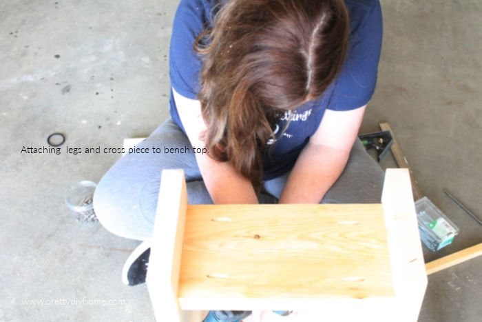 Attaching the lower portion of a wood bench to the top seat portion using a screw driver.