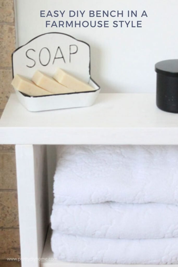 A sturdy DIY Bench made from wood and stained white with a soap dish and black candle in a bathroom.