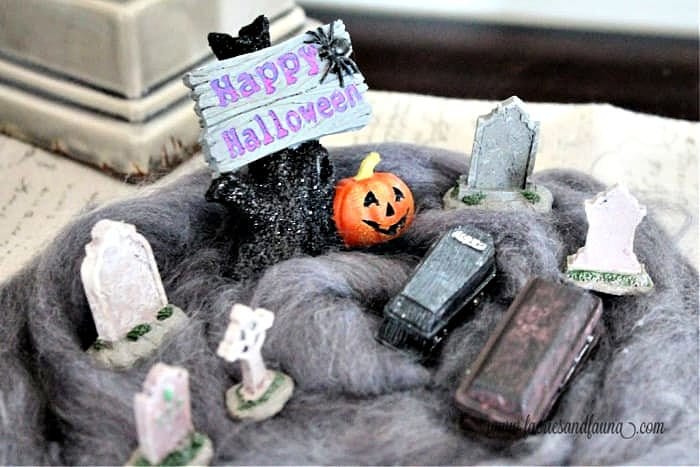 A Halloween Diorama of a grave yard with a miniature coffin, gravestones and Happy Halloween sign.