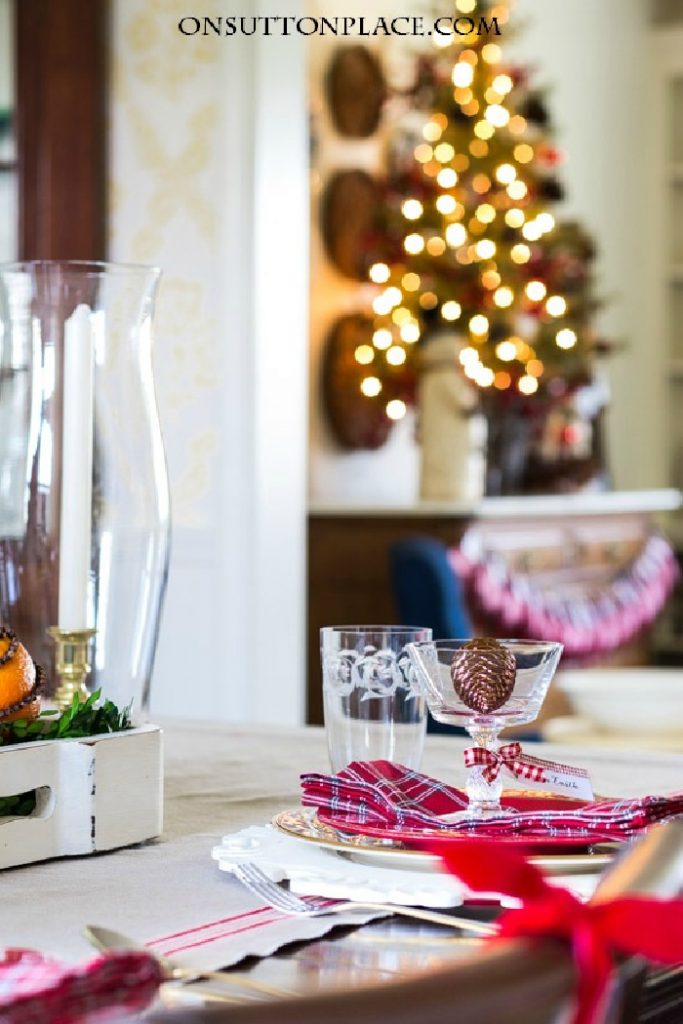 Traditionally decorated Christmas dining room setting in red with a Christmas tree in the background.