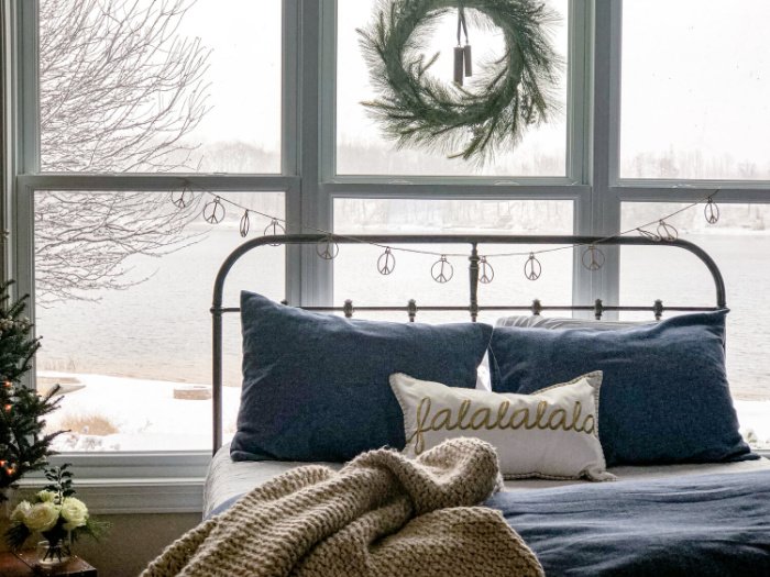 A Christmas bedroom home tour, with a large bed sitting in front of a gorgeous window with an ice covered lake in the background.