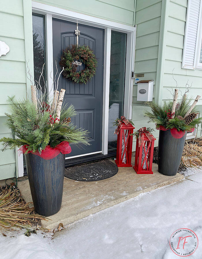 Two large red DIY Christmas lanterns sitting on the front porch for the holidays.