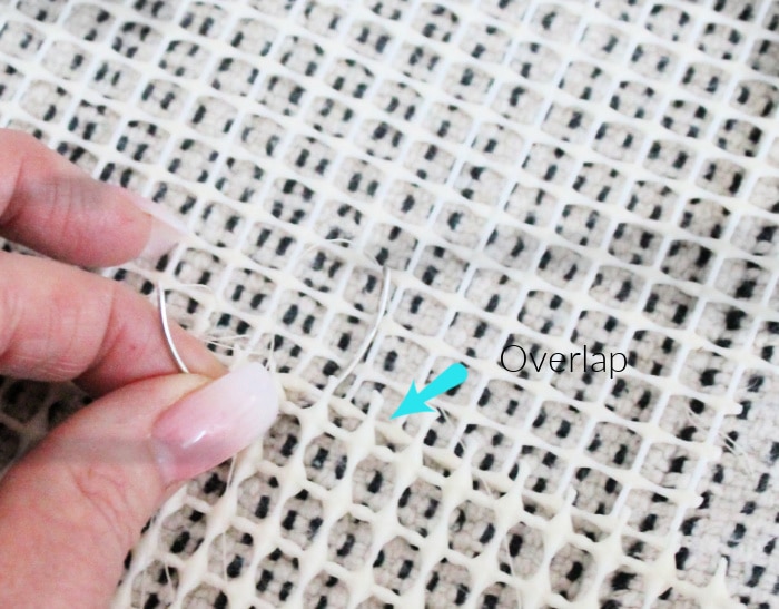 A close up of a round needle sewing non slip backing to the back of an IKEA rug