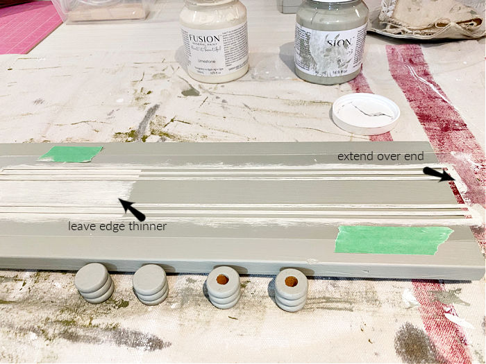 Placement of a grain sack stencil on a eucalyptus green painted table riser project, with arrows giving placement tips