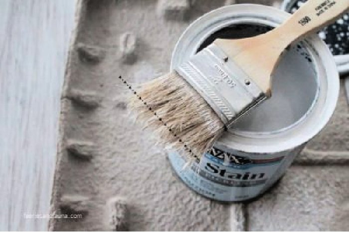 A dollar store chippy brush laying over a can of stain while refinishing a coffee table.