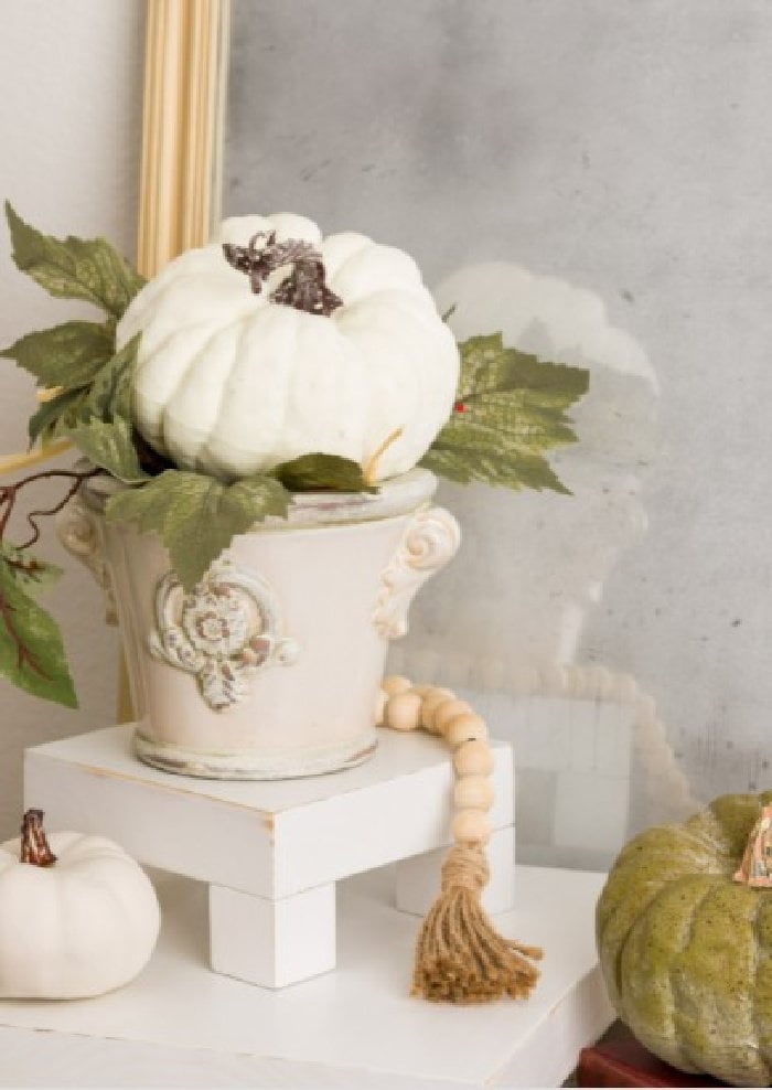 A handmade wood table riser with a farmhouse beads and green and white pumpkins