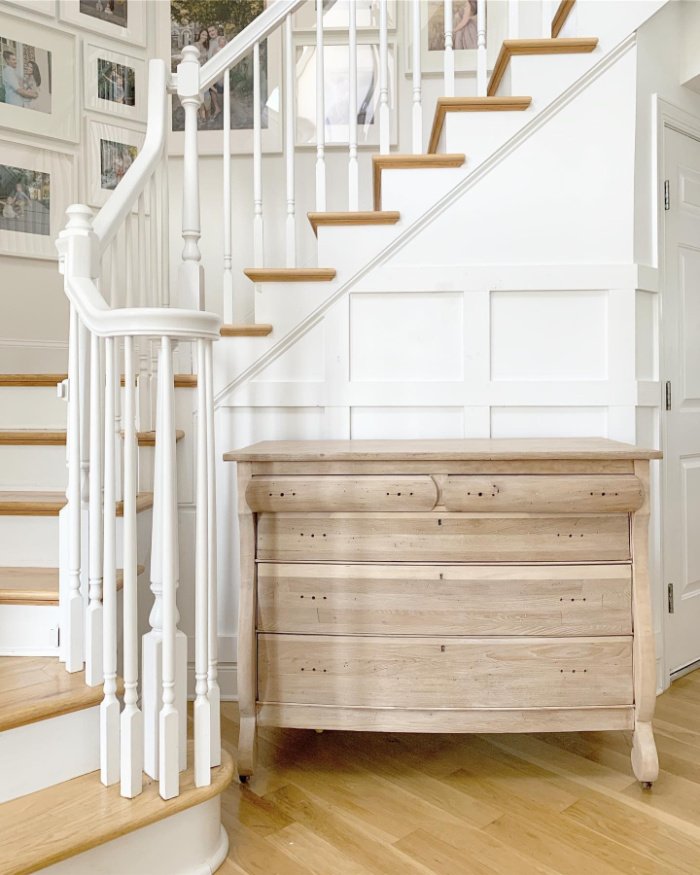 A beautiful lime wax glazed antique dresser surrounded by a white bannister. The dresser has been made over with the veneer removed.