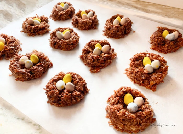 A dozen large birds nest Easter cookies sitting on a parchment lined sheet.