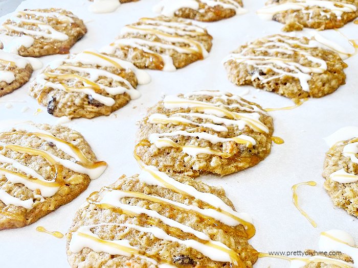 Carrot cookies on parchment paper drizzled with cream cheese icing and then caramel sauce.