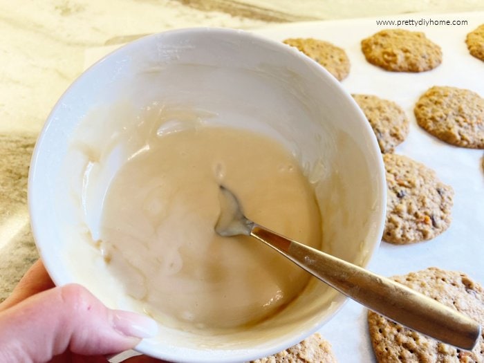 A bowl full of cream cheese drizzle for carrot cookies.