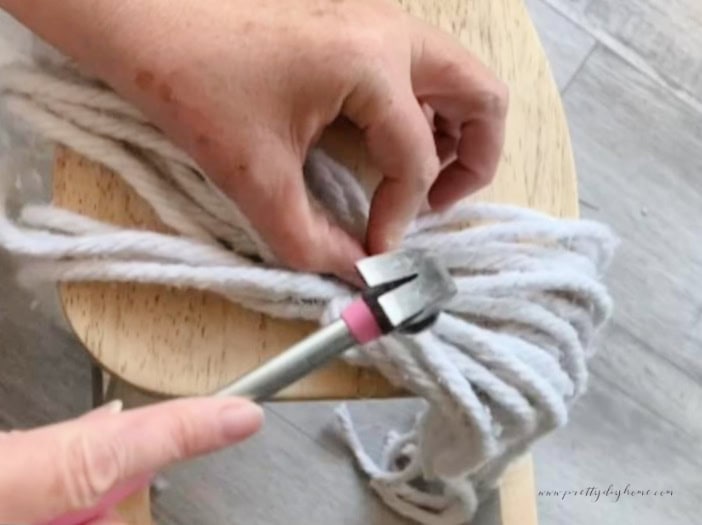 Attaching a rope tail to the end of a vintage rocking horse using cut tacks and a small hammer.