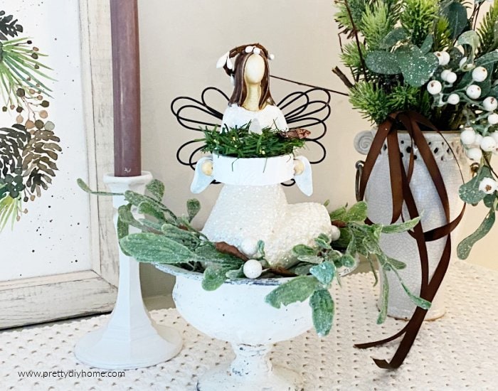 DIY Christmas ornament made from a thrift store angel. The angel is now white with lots of sparkles and a natural branch looking hallow. She is surrounded by other neutral Christmas decor.