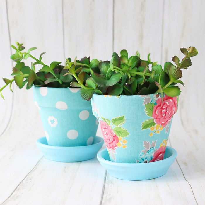 Two cheerfully coloured blue clay pots decorated in bright Spring blue fabric. An easy clay pot craft idea.