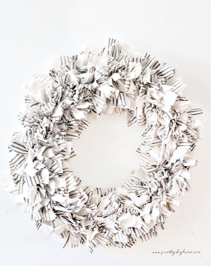 A large wreath in neutral colors made using cream, white and grey fabric ties into a rag wreath.